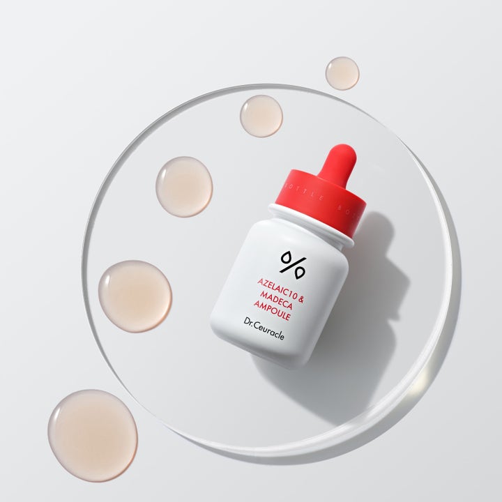 Dr. Ceuracle Azelaic 10 & Madeca Ampoule 30 ml rauhoittava seerumi ja pisaroita lasialustalla.