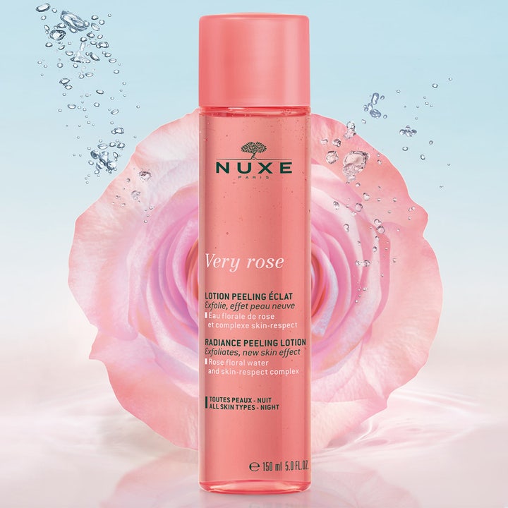 Nuxe Very Rose Peeling Lotion 150 ml kirkastava kuoriva kasvovesi vaaleanpunaisessa pullossa ruusun ja kuplien ympäröimänä.