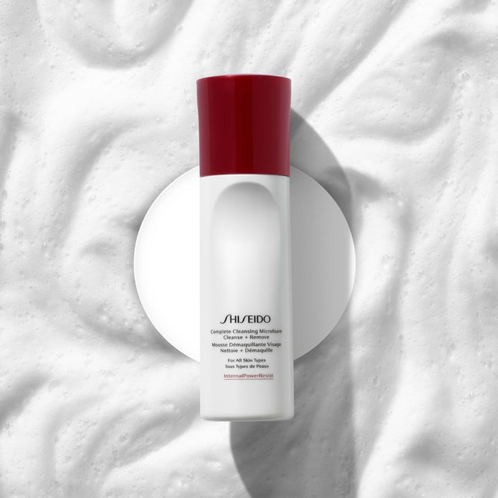 Shiseido Complete Cleansing Microfoam 180 ml puhdistusvaahto valkoisessa pullossa ilmavan vaahdon päällä