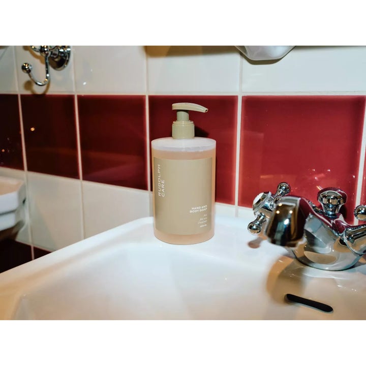 Rudolph Care Hand And Body Soap 500 ml puhdistava suihkusaippua beigessä pumppupullossa pesualtaan reunalla