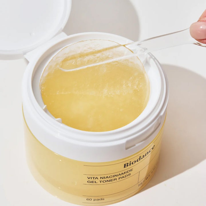Kirkastava Biodance Vita Niacinamide Gel Toner Pads 60 kpl kasvovesi läpikuultavassa lasipurkissa ja yksi puhdistuslappu.