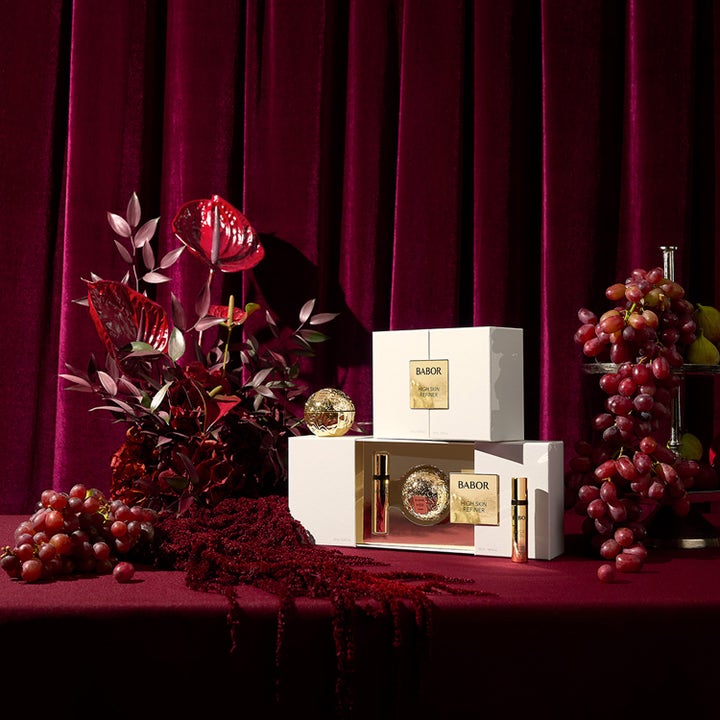 Babor HSR Gift Set 60 ml kiinteyttävä ihonhoitosetti valkoisissa rasioissa punaisen sametin ja rypäleiden keskellä.