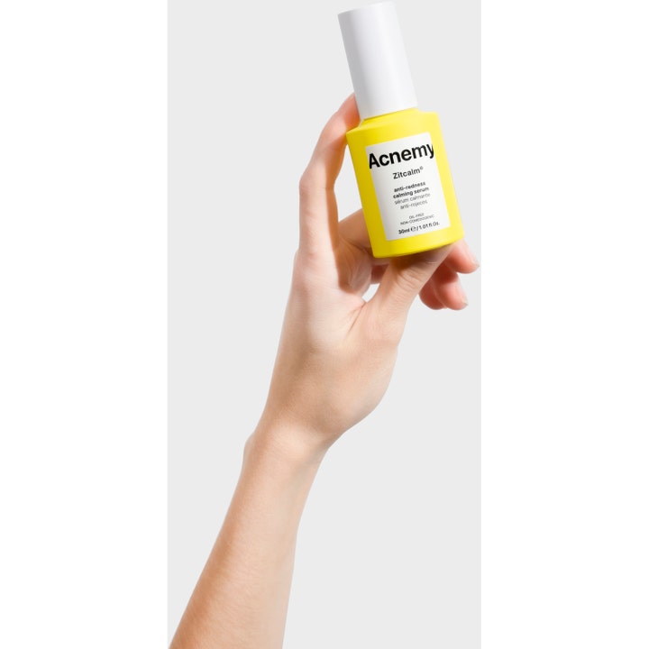 Niche Beauty Lab Acnemy Zitcalm Serum 30 ml rauhoittava seerumi keltaisessa pullossa kädessä pidettynä.