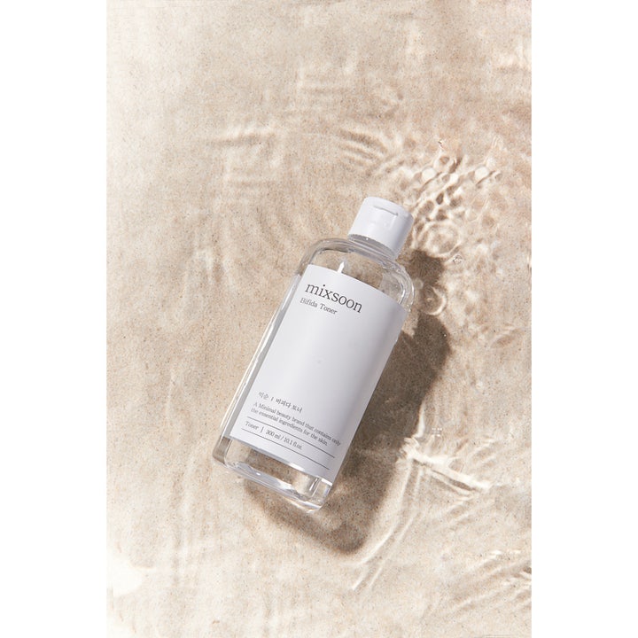 Mixsoon Bifida Toner 300 ml vahvistava kasvovesi kirkkaassa pullossa hiekkaisella rannalla veden äärellä.