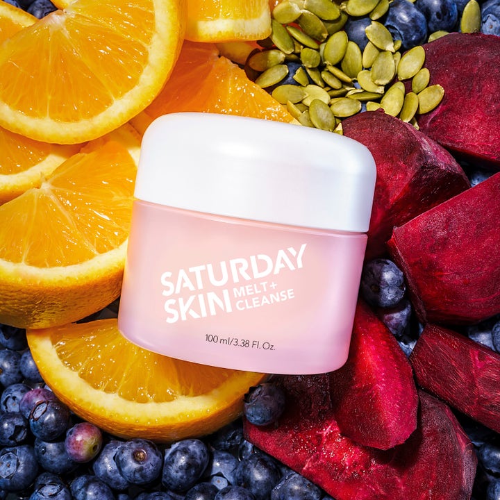 Saturday Skin Melt + Cleanse 100 ml puhdistusbalmi vaaleanpunaisessa purkissa appelsiinien ja marjojen keskellä.
