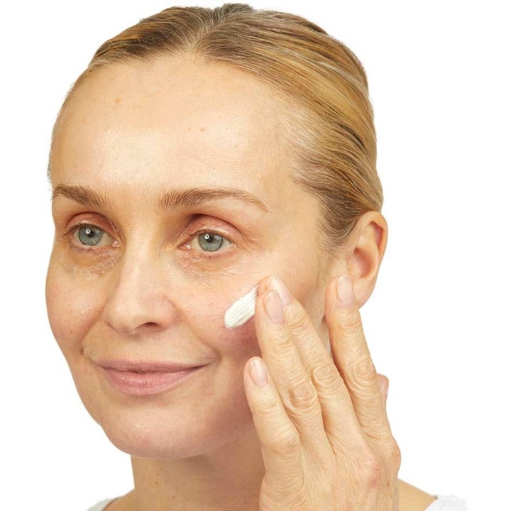 No7 Skincare Essential Set 80 ml kiinteyttävä ihonhoitosetti nainen levittää valkoista voidetta poskelleen