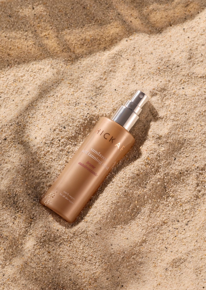 Hickap Sundazed Self Tanning Mist 100 ml päivettävä kasvosuihke hiekalla olevassa pronssisessa pullossa.