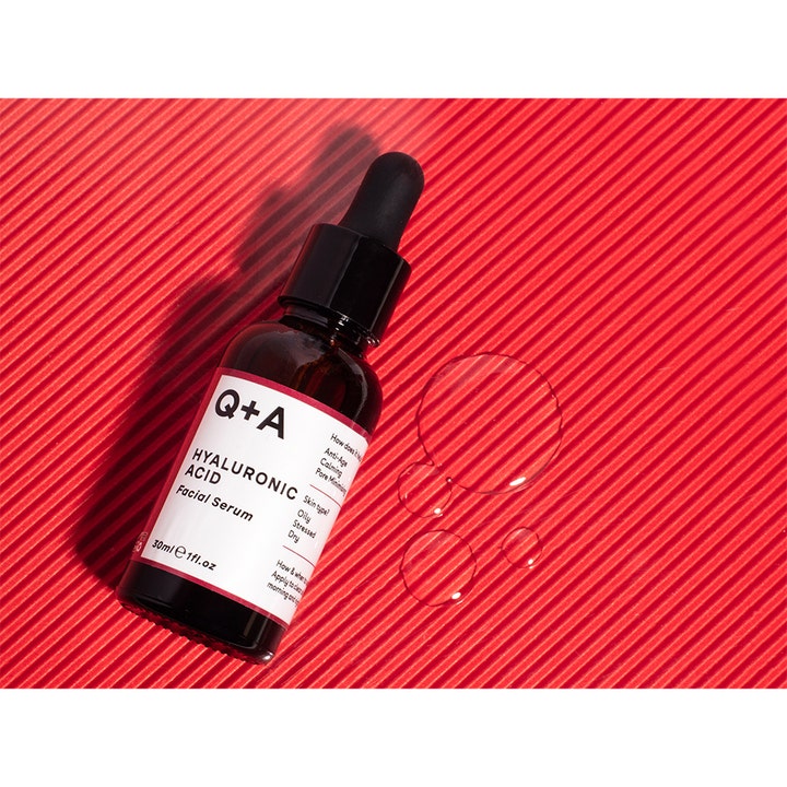 Q+A Hyaluronic Acid Facial Serum 30 ml kosteuttava seerumi tummassa lasipullossa kirkkailla pisaroilla punaisella pohjalla.