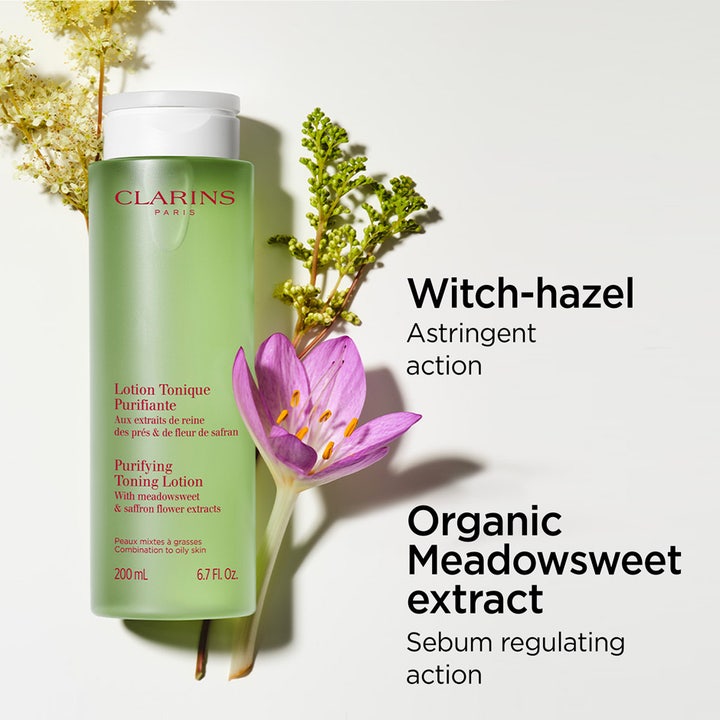 Clarins Purifying Toning Lotion 200 ml puhdistava kasvovesi vihreässä pullossa kukkien ja kasvien rinnalla.