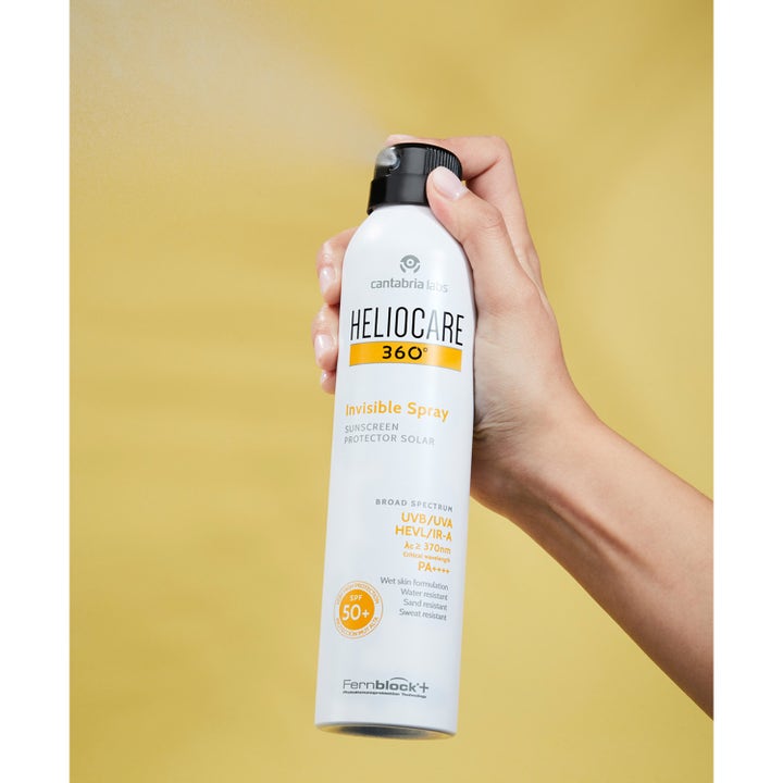 Heliocare Invisible Spray SPF 50+ 200 ml aurinkovoide, jota kÀsi suihkuttaa hienona sumuna keltaisella taustalla.