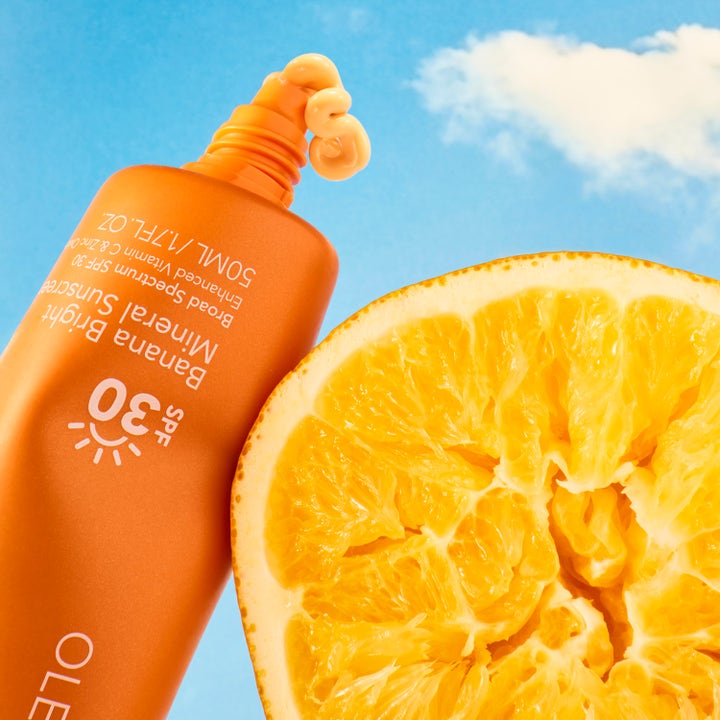 Ole Henriksen Truth Banana Bright Mineral Sunscreen SPF30 50 ml aurinkovoide ja appelsiini sinistä taivasta vasten