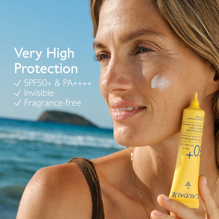 Caudalie Vinosun Lightweight Fluid SPF50 40 ml hajusteeton aurinkovoide kasvoille keltaisessa tuubissa rantamaisemassa.