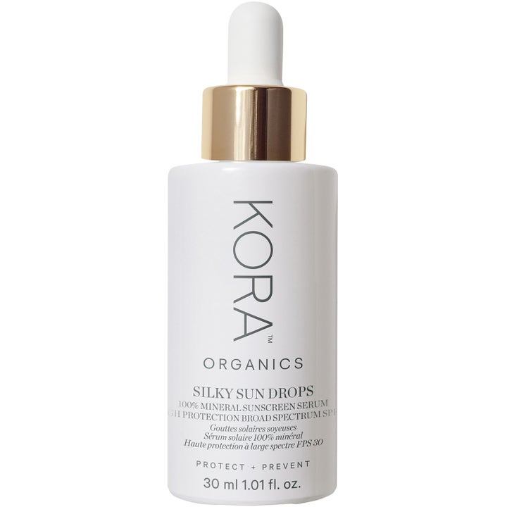 Kora Organics Silky Sun Drops 30 ml suojaava aurinkosuoja-seerumi valkoisessa pullossa kultaisella pipettikorkilla.