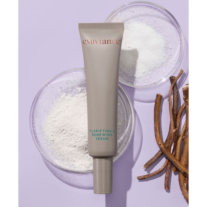 Exuviance Clarifying and Renewing Serum 30 ml kirkastava ja uudistava seerumi harmaassa tuubissa jauheen ja oksien kanssa.