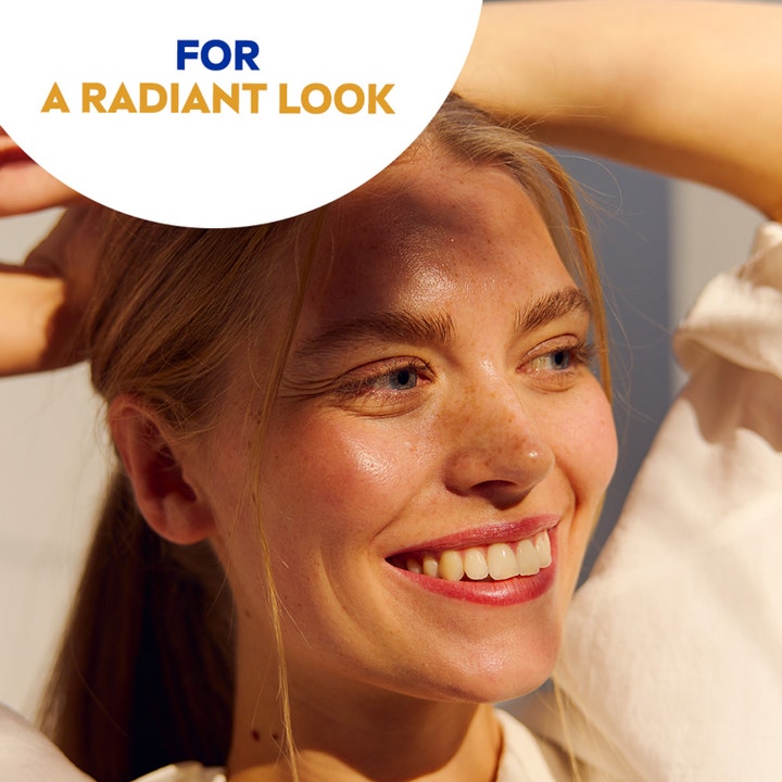 NIVEA Sun UV Face Anti Age Q10 Cream 50 ml aurinkovoide kasvoille antaa heleyttä ja kuvassa on hymyilevä nainen auringossa.