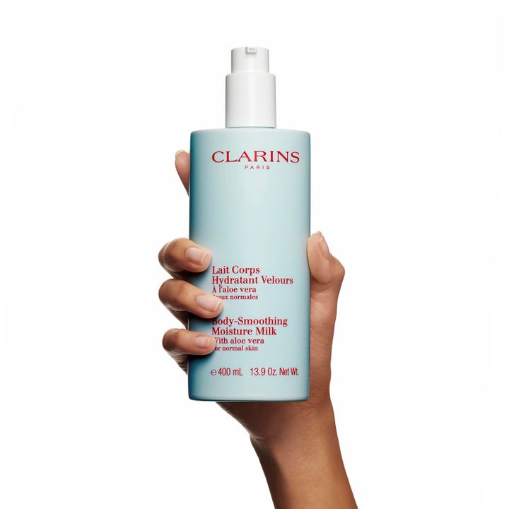 Clarins Hydrating Body-Smoothing Moisture Milk 400 ml silottava vartaloemulsio vaaleansinisessä pumppupullossa kädessä.