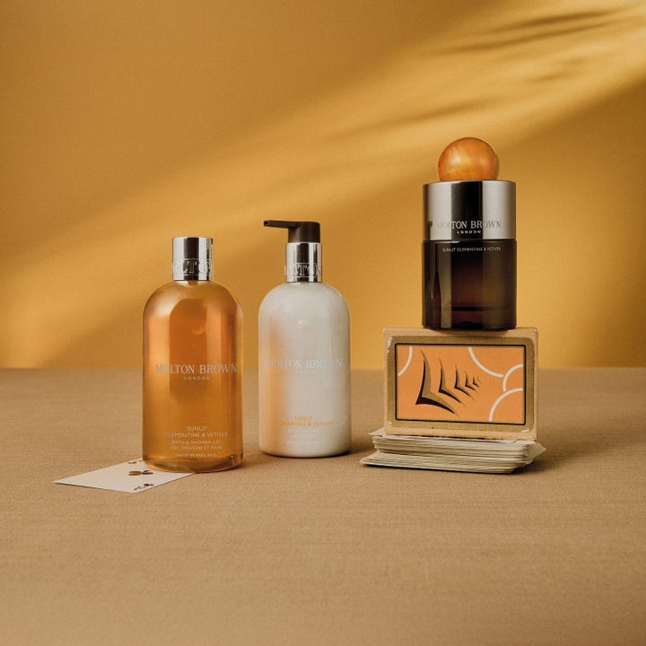 Molton Brown Sunlit Clementine & Vetiver 300 ml kosteuttava vartalovoide valkoisessa pumppupullossa aurinkoisessa asetelmassa.