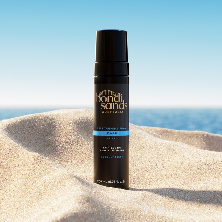 Bondi Sands Self Tanning Foam Dark 200 ml itseruskettava vaahto mustassa pullossa hiekkarannalla.