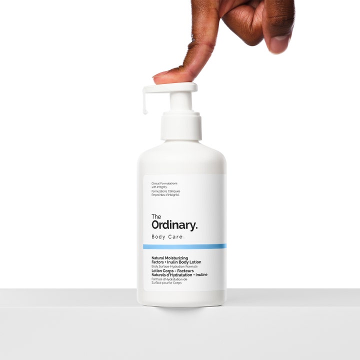 The Ordinary NMF + Inulin Body Lotion 240 ml kosteuttava vartalovoide valkoisessa pumppupullossa sormella painettuna