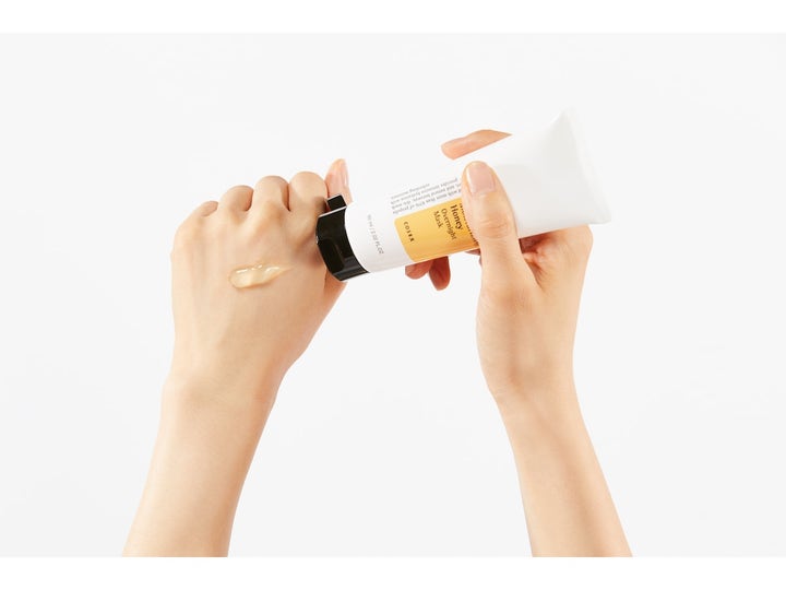 COSRX Ultimate Moisturizing Honey Overnight Mask 60 ml kosteuttava yönaamio ja kultainen geelikoostumus kädellä.