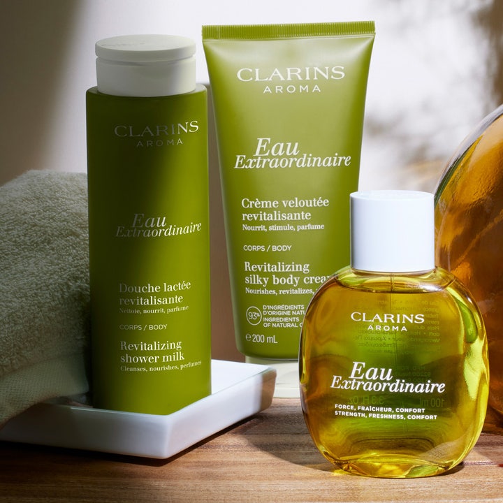 Clarins Eau Extraordinaire Revitalizing Shower Milk 200 ml elvyttävä suihkumaito vihreässä pullossa kylpyasetelmassa.
