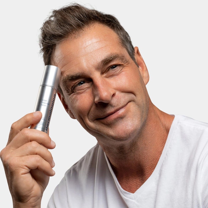 Dermalogica Smart Response Serum 30 ml heleyttävä kasvoseerumi hopeisessa pullossa hymyilevän miehen pitelemänä