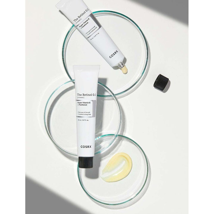 COSRX The Retinol 0.1 Cream 20 ml silottava kasvovoide tuubeissa ja keltaista voidetekstuuria lasiastioissa.