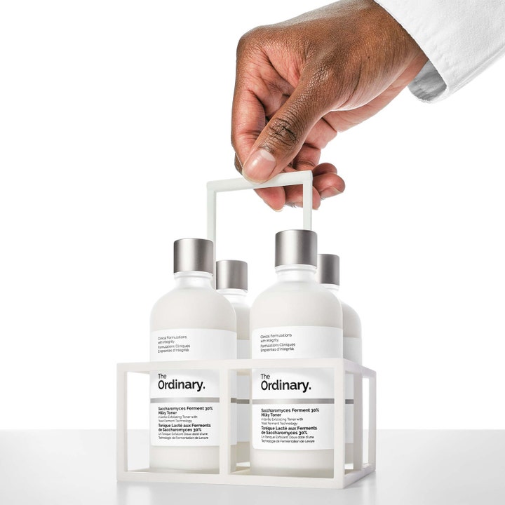 The Ordinary Saccharomyces Ferment 30% Milky Toner 100 ml neljä pulloa valkoisessa telineessä kädessä.