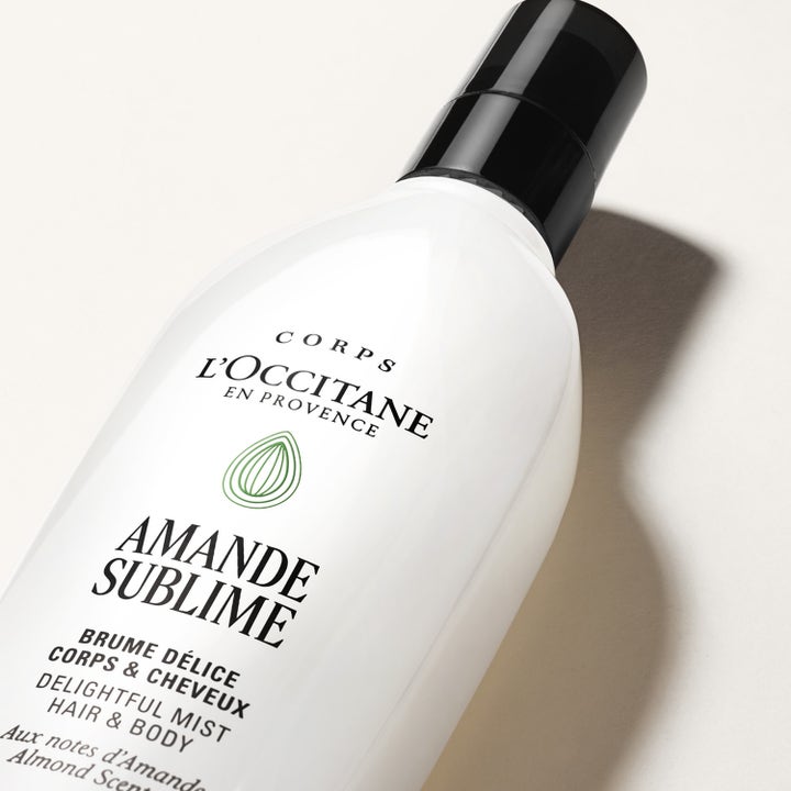 L'Occitane en Provence Almond Hair Body Mist 100 ml raikastava vartalosuihke valkoisessa pullossa mustalla korkilla.