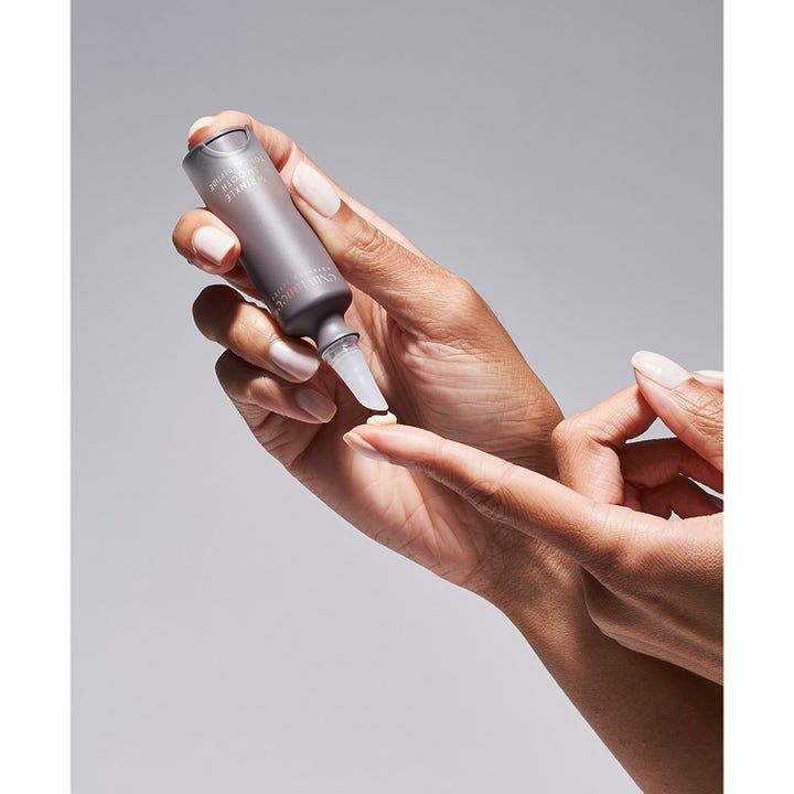 Exuviance Wrinkle Smooth Topical Peptide 5 g silottava seerumi harmaassa tuubissa levitettynä sormenpäälle.