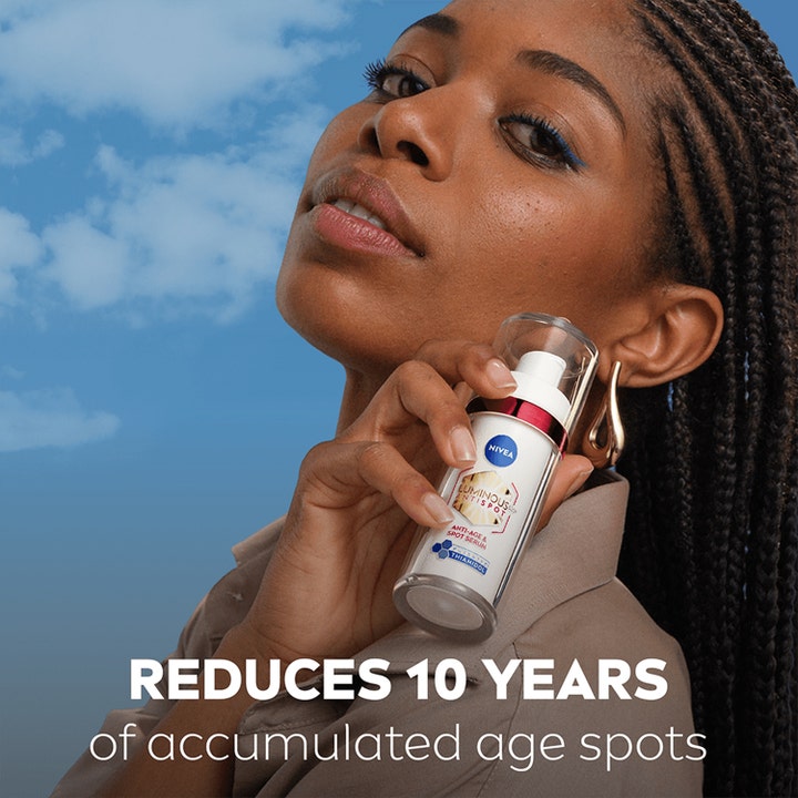Nivea Luminous 630 Anti-Age & Dark-Spot Serum 30 ml häivyttää ikäläiskiä nainen pitelee pulloa taivasta vasten.