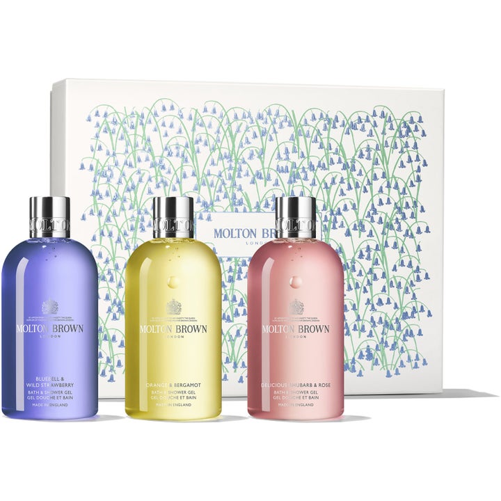 Molton Brown Floral & Fruity 3x300 ml suihkugeelisetti luo raikkaan tunteen kolmella värikkäällä pullolla kukkalaatikon edessä.