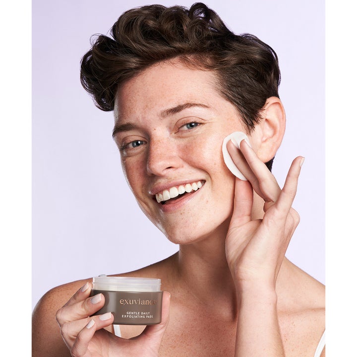 Exuviance Gentle Daily Exfoliating 60 Pads kirkastavat kuorintalaput nainen levittää lappua kasvoilleen.