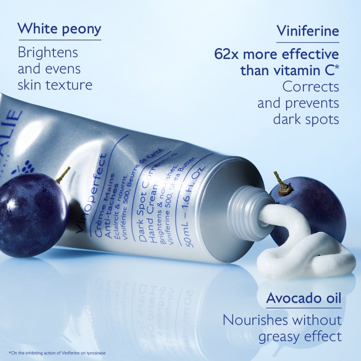 Caudalie Vinoperfect Dark Spot Correcting Hand Cream 50 ml käsivoide ja valkoista voidetta viinirypäleiden kera.