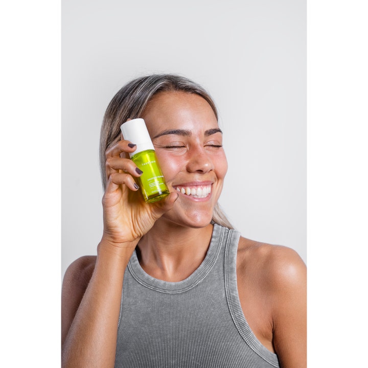 Niche Beauty Lab Theramid Smoothing Treatment 30 ml tasoittava yöseerumi vihreässä pullossa hymyilevän naisen kädessä.