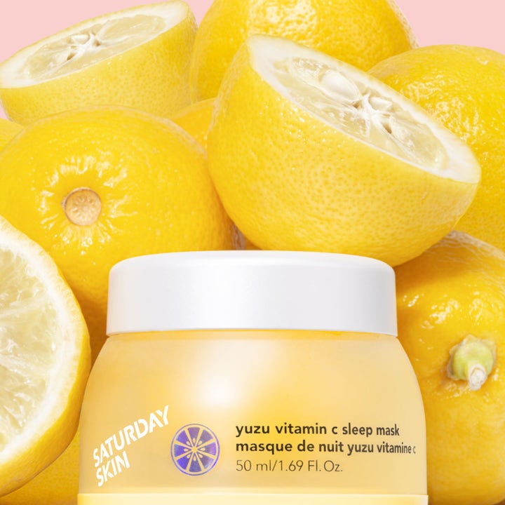Kirkastava Saturday Skin Yuzu Vitamin C Sleep Mask 50 ml yönaamio keltaisessa purkissa yuzu-hedelmien ympäröimänä.