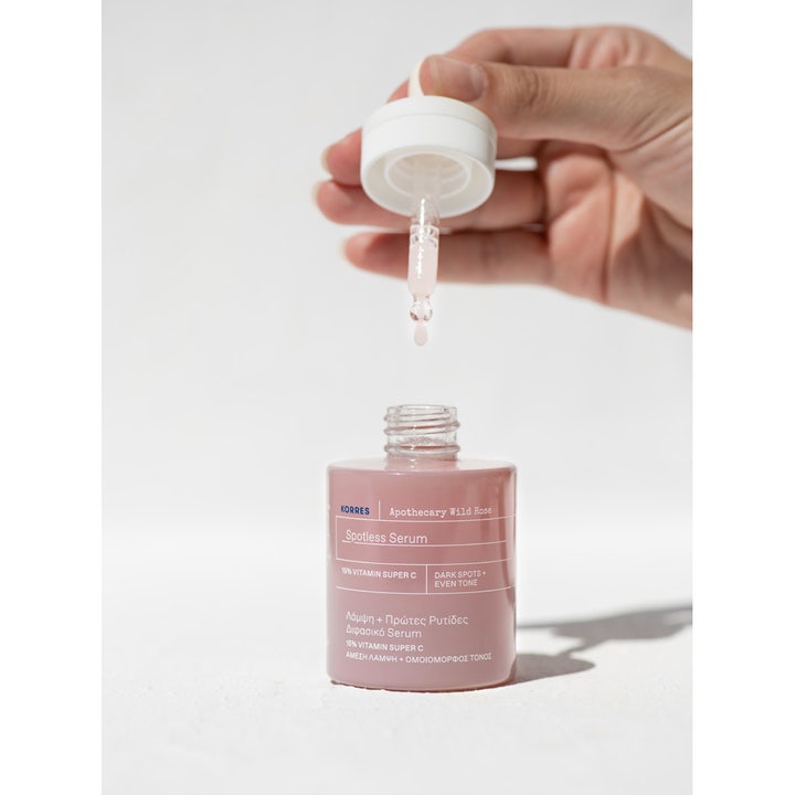 KORRES Apothecary Wild Rose Spotless Serum 30 ml kirkastava C-vitamiiniseerumi ja pipetti tiputtamassa tuotetta pulloon.