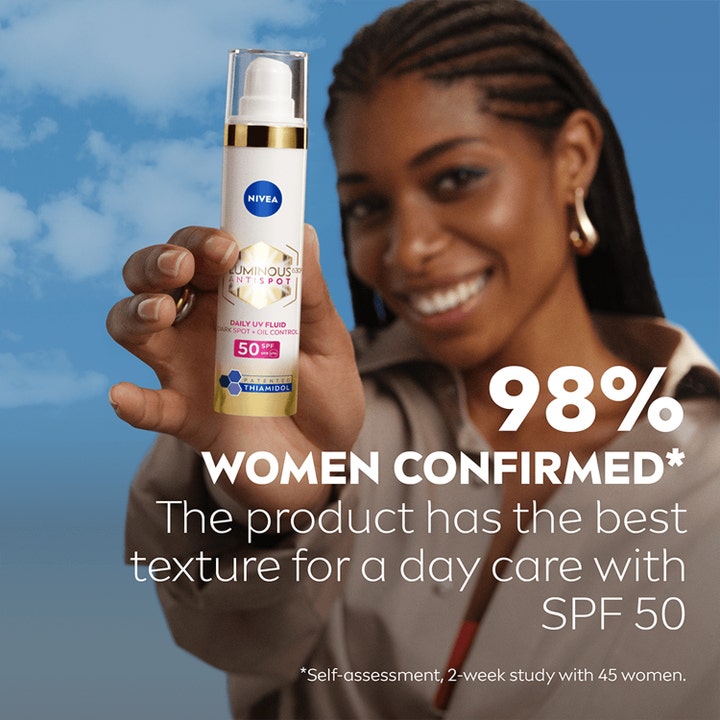 NIVEA Luminous630 Anti Dark-Spot Day Fluid 40 ml aurinkosuojavoide nainen pitelee SPF 50 pumppupulloa taivasta vasten