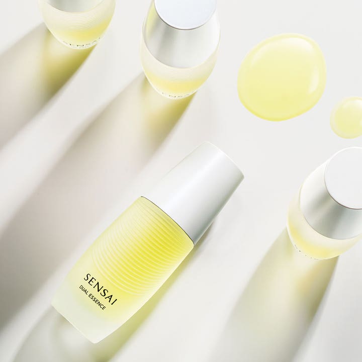 Sensai Dual Essence 30 ml heleyttävä hoitoneste huurretussa lasipullossa keltaisilla pisaroilla.