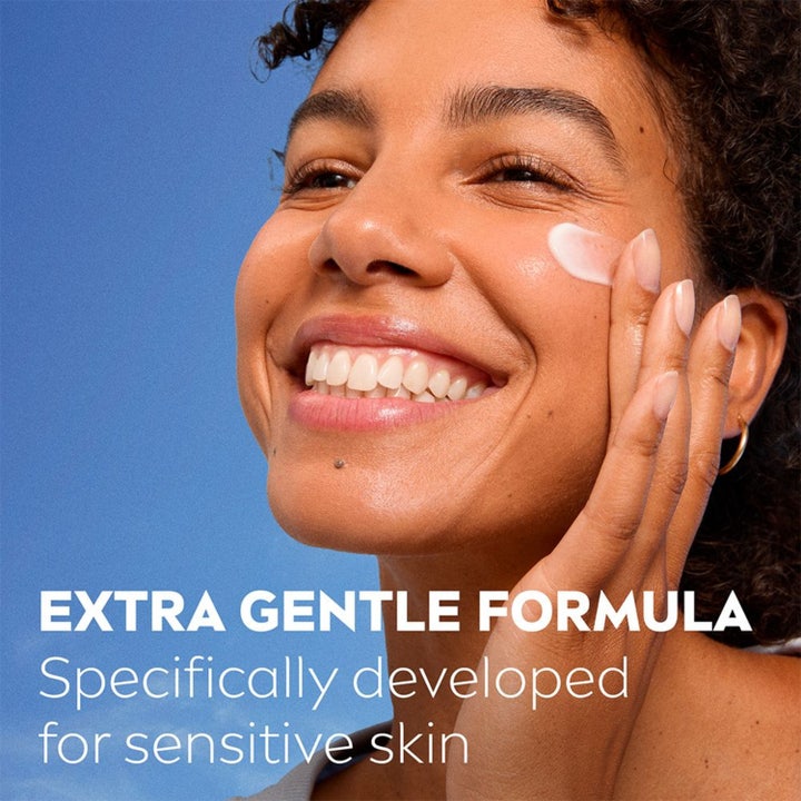 NIVEA Soothing Day Cream 50 ml rauhoittava päivävoide, hymyilevä nainen levittää hellävaraista koostumusta iholleen.