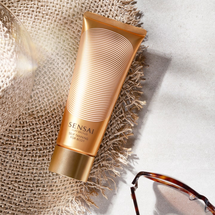 Sensai Silky Bronze Self Tanning For Body 150 ml hehkua antava itseruskettava kultaisessa tuubissa olkihatun päällä