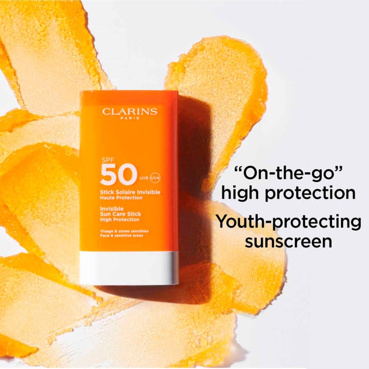 Clarins Invisible Sun Care Stick 17 g SPF 50 aurinkovoide kasvoille on oranssi puikko oranssien tuotevetojen päällä.