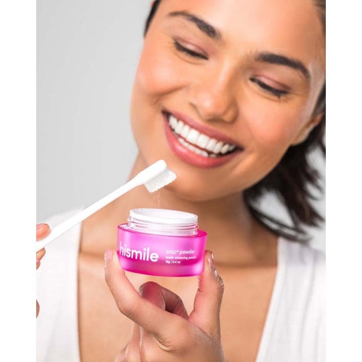 Hismile Whitening Set 12 g hampaiden valkaisuun kirkastaa hymyn nainen kastaa harjan pinkkiin pap+ powder -purkkiin.