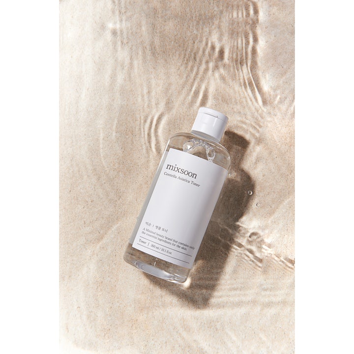 Mixsoon Centella Asiatica Toner 300 g rauhoittava kasvovesi kirkkaassa pullossa hiekan ja veden päällä.