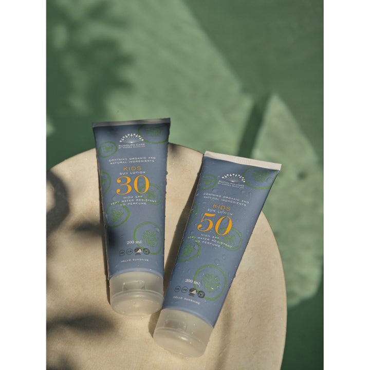 Rudolph Care Sun Lotion Kids SPF30 200 ml vedenkestävä aurinkovoide kahdessa sinisessä tuubissa vesipisaroilla.