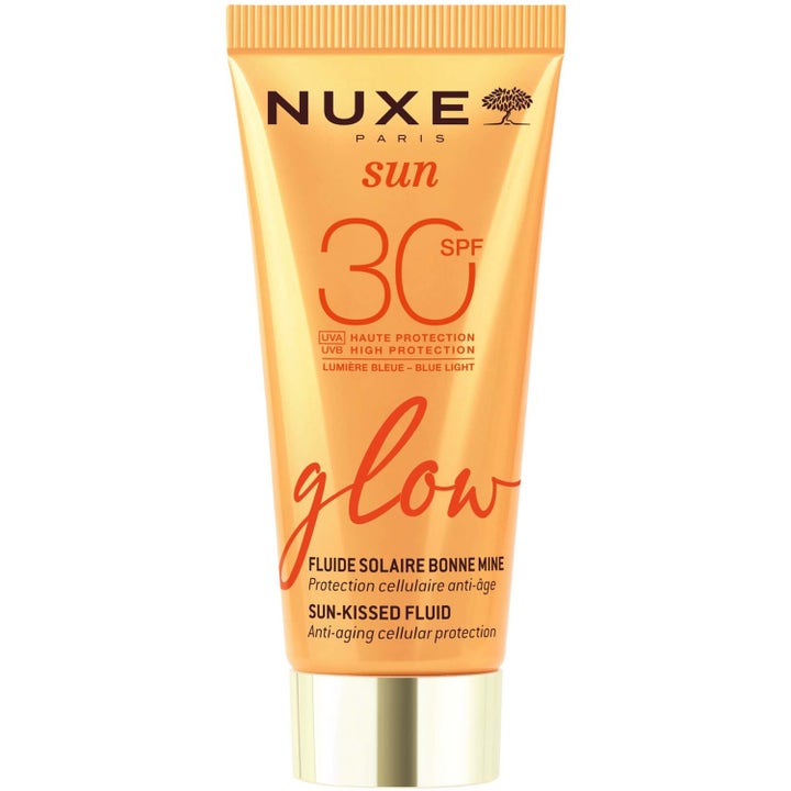 Nuxe Sun Glow SPF 30 Sun-Kissed Fluid hehkua antava aurinkovoide oranssissa tuubissa, jossa on kullanhohtoinen korkki.
