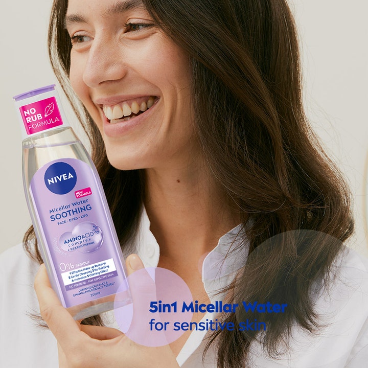 NIVEA Micellar Water Soothing 200 ml puhdistusvesi, jota hymyilevä nainen pitelee kädessään herkälle iholle.