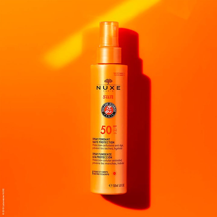Nuxe Sun Face and Body Milk SPF50 150 ml aurinkovoidesuihke oranssissa pullossa keltaisella taustalla
