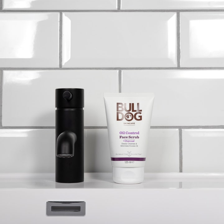 Bulldog Oil Control Face Scrub 125 ml kuorinta-aine valkoisessa tuubissa mustan hanan vieressä kylpyhuoneessa