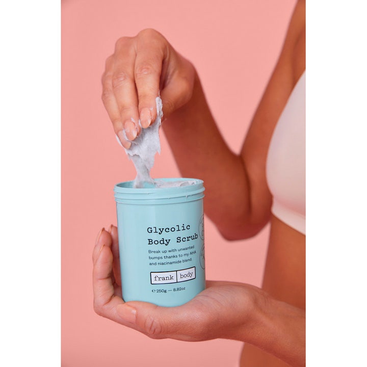 Frank Body Glycolic Body Scrub 250 g kuorinta-aine vaaleansinisessä purkissa, josta otetaan sormin vaaleaa massaa.
